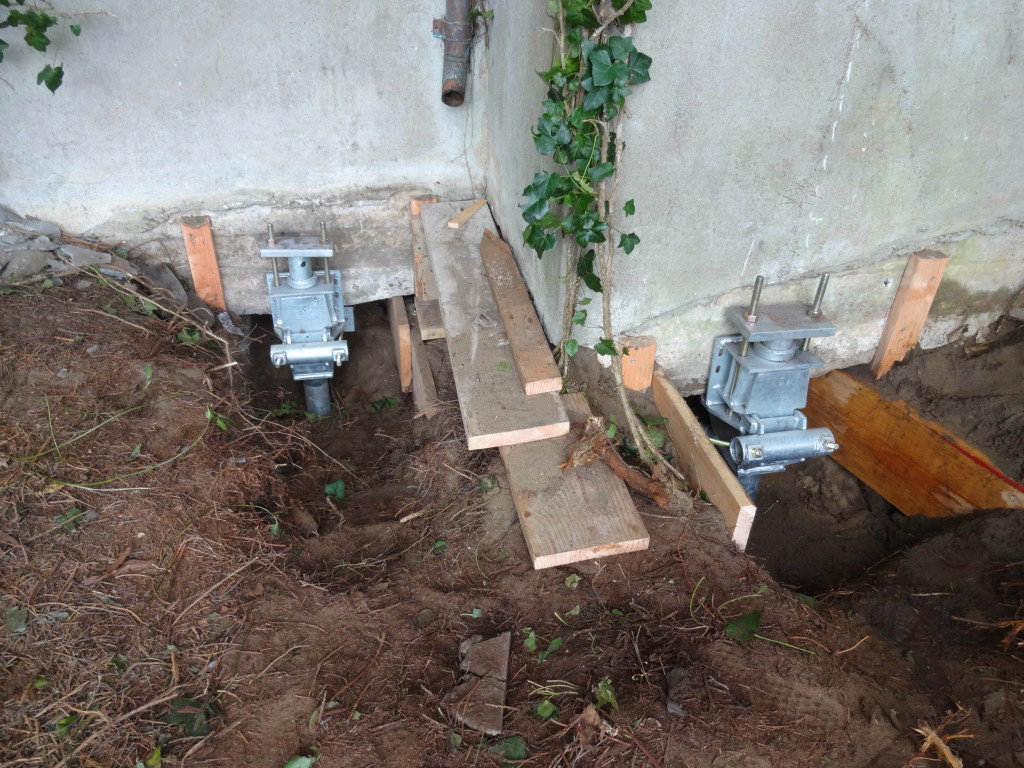 Underpinning of existing foundation with helical anchors; top brackets showing.
